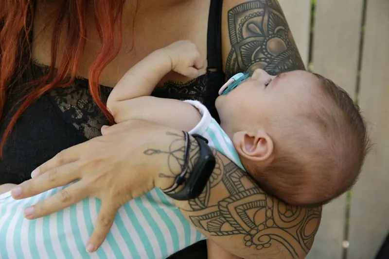 mother holding her baby in tattooed arms