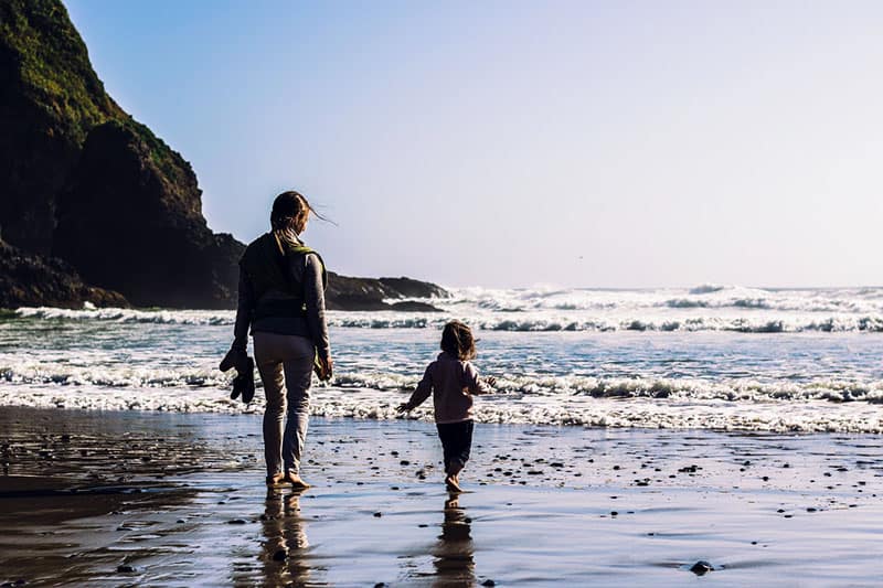 mother walking on the beach with her little girl