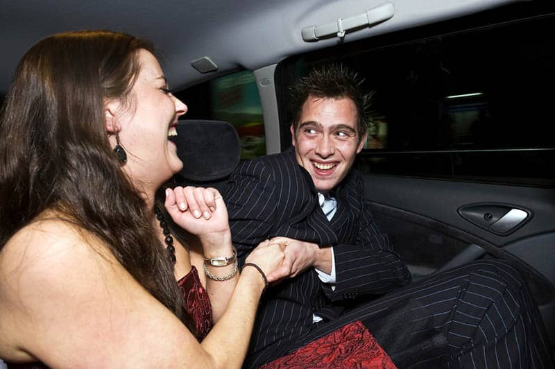 photo of smiling man and woman in backseat car