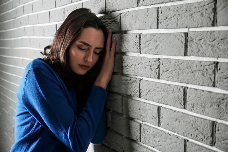 sad woman standing by the wall