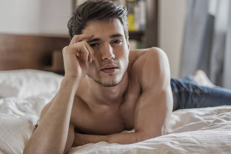 uomo sexy sdraiato sul letto e in posa