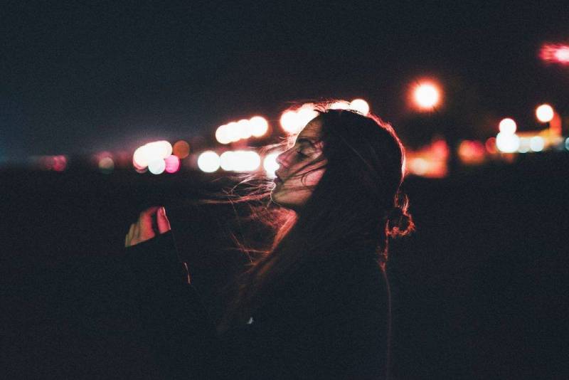 side view of girl's messed hair by wind during night