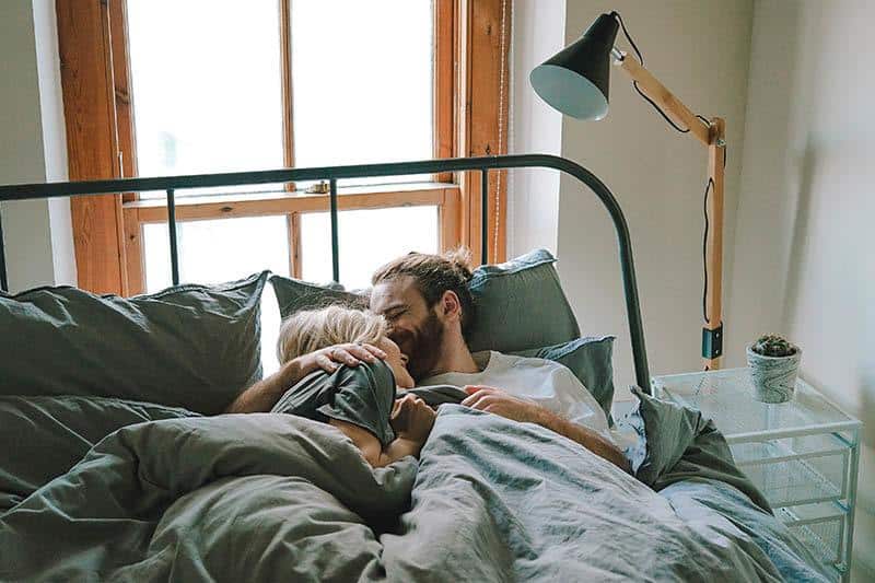 smiling couple lying on bed
