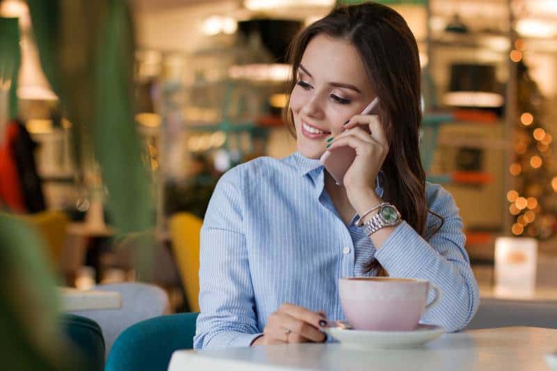 chica sonriente hablando por teléfono en un café