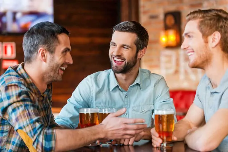 smiling male friends talking and drinking beer