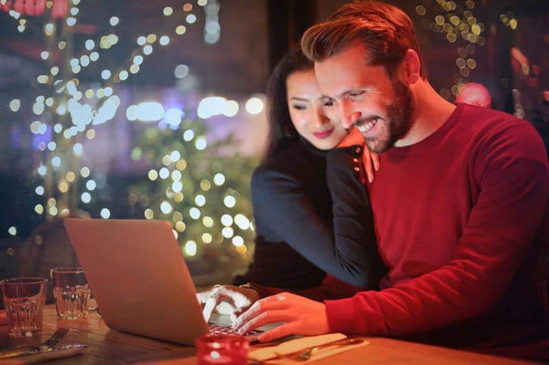 smiling man and woman looking at laptop
