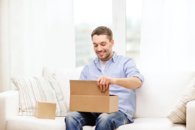 smiling man opening cardboard boxes