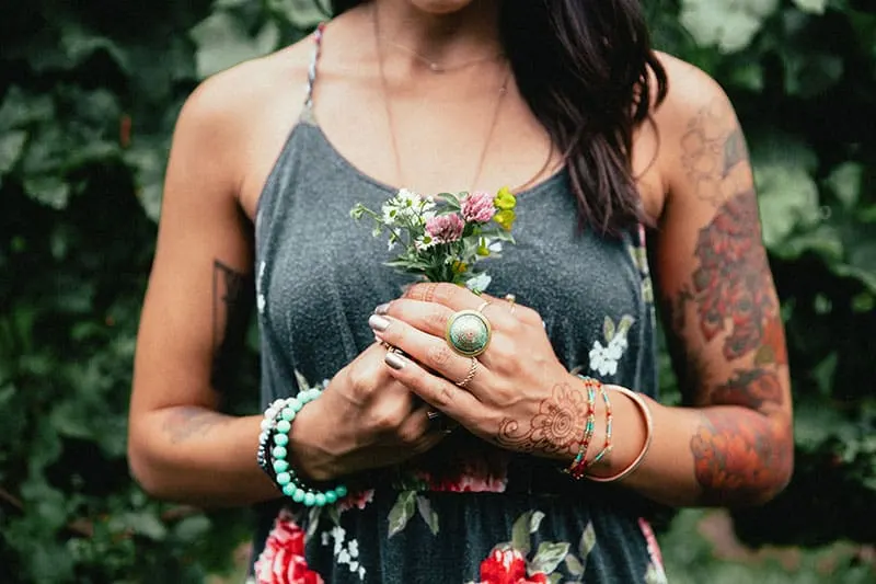 tattooed woman holding flowers in hands