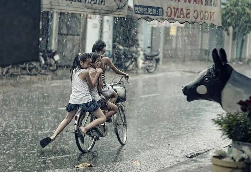 three child riding bicycle on rain