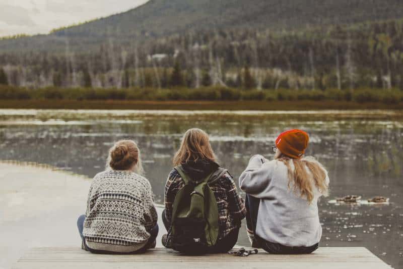 three female friends sitting by the lake