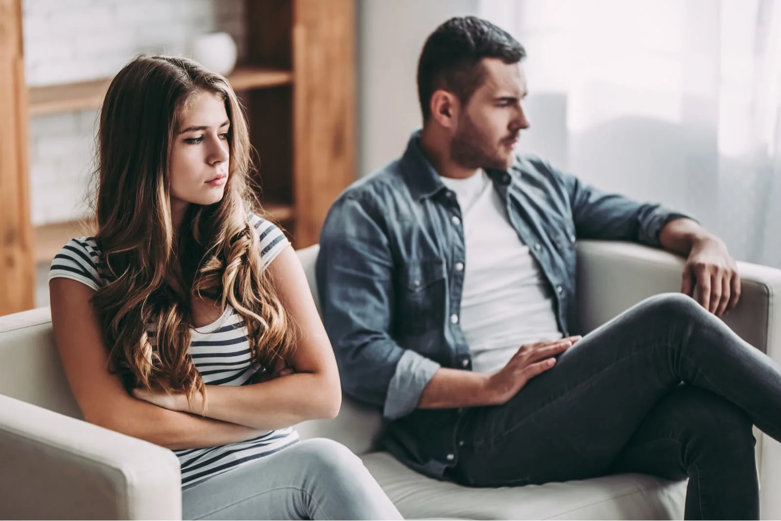 unhappy woman sitting next to her boyfriend on the couch