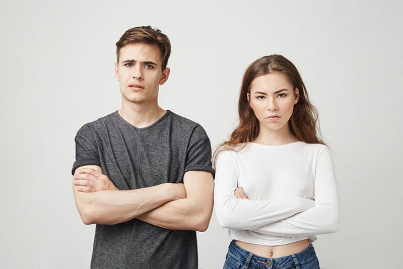 upset man and woman standing next to each other with crossed arms