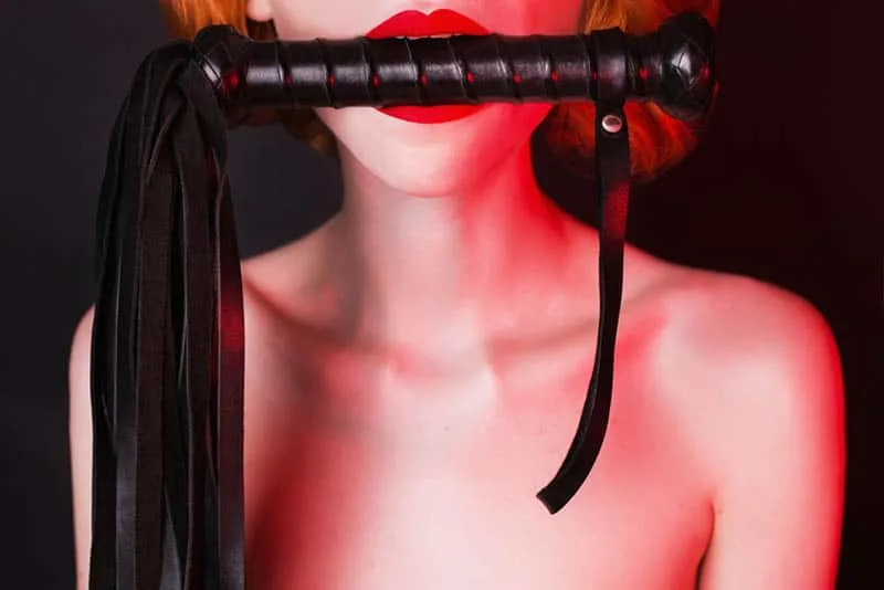 woman holding whip in her mouth