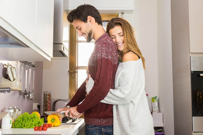 woman hugging a man who is cooking