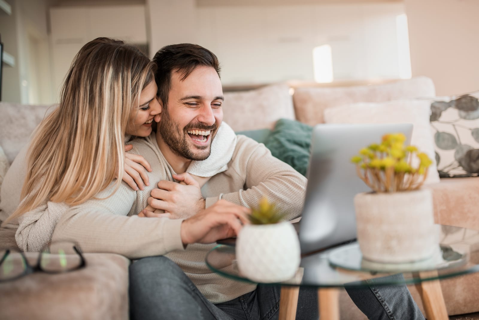 woman hugging smiling man who works on laptop