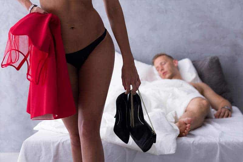 donna in biancheria intima che esce di casa mentre l'uomo dorme sul letto