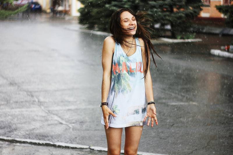 woman in white tank top and blue standing on road during rain