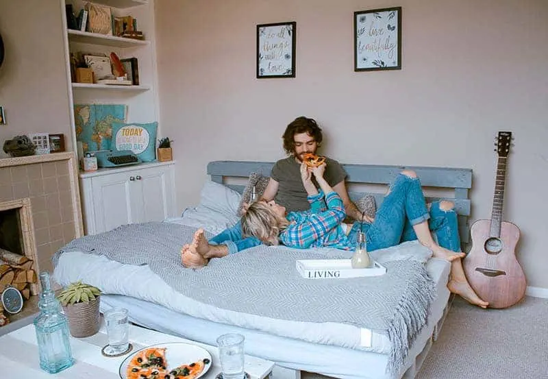 woman lying on bed and giving pizza to her boyfriend