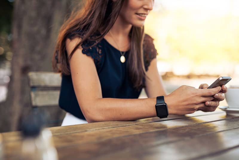 woman typing on phone while sitting outdoor