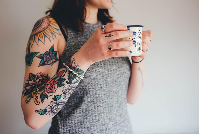 donna con tatuaggi di fiori colorati sul braccio