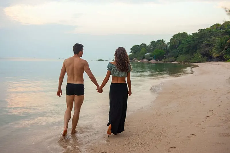 Cheerful couple having some good time naked on the beach