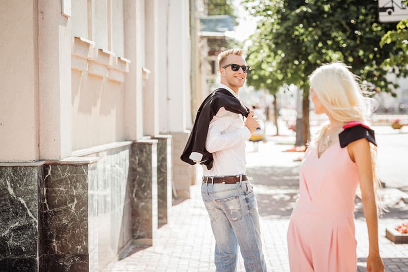 young man looking at blond woman on the street