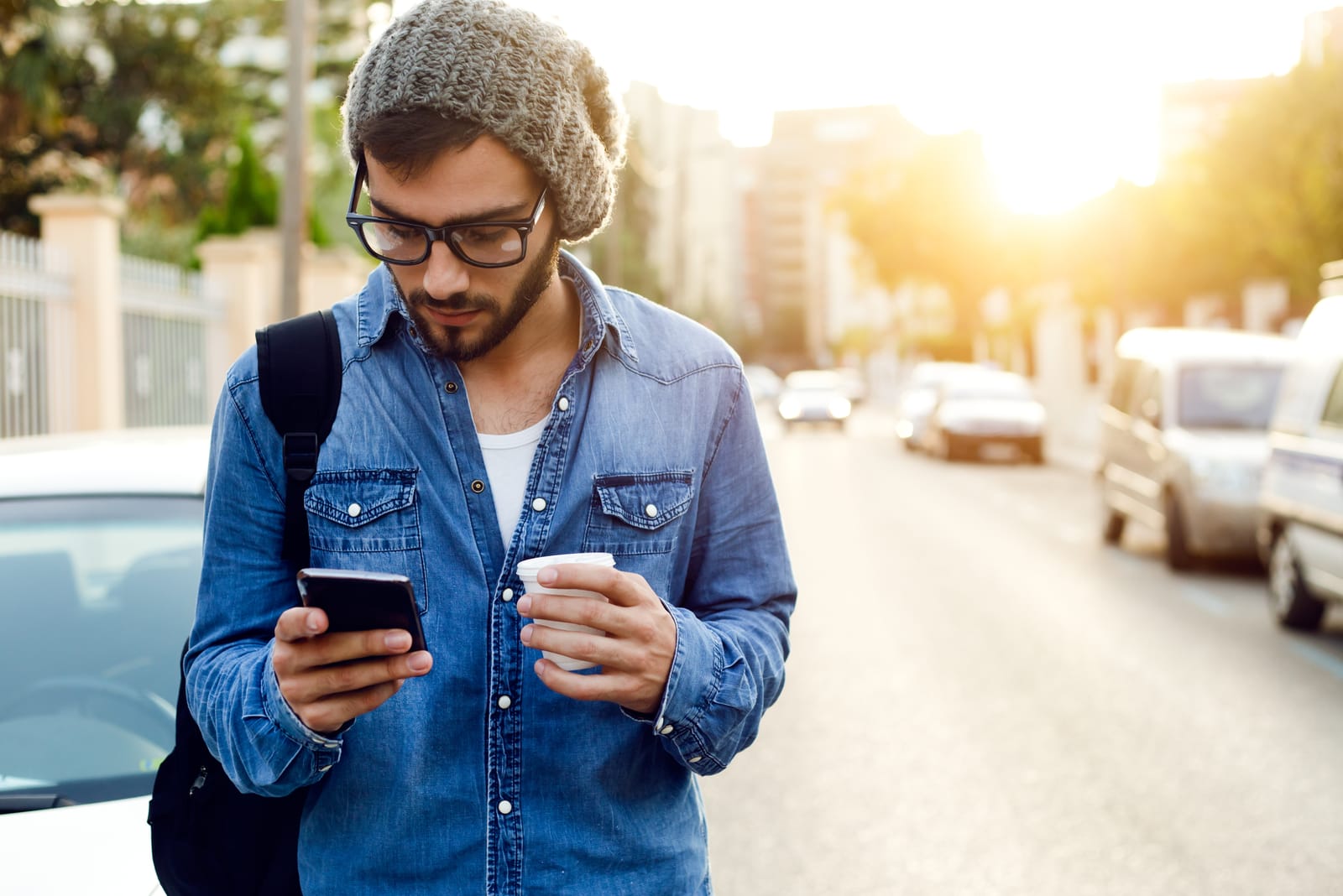 giovane uomo con occhiali da sole che tiene in mano il telefono