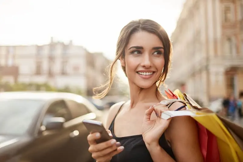 young woman standing on the street with shopping bags
