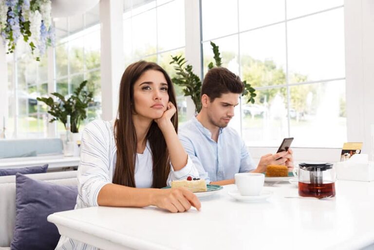 bored woman sitting while man typing on phone