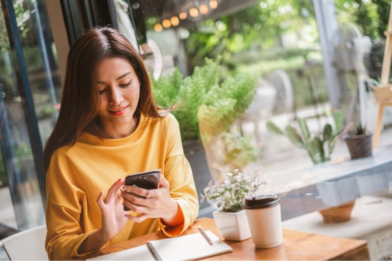 a young asian woman with a smile uses a cell phone