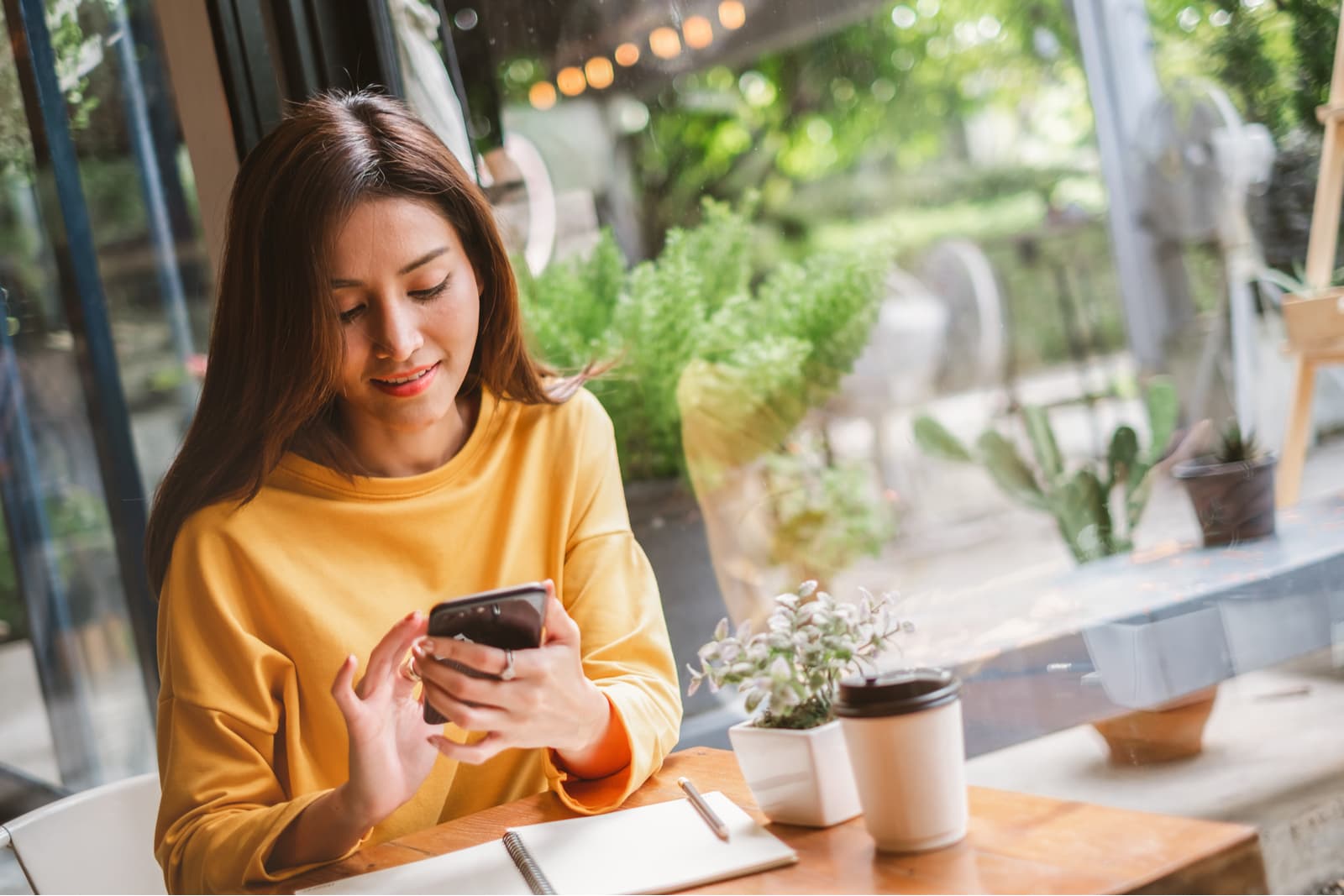 a young asian woman with a smile uses a cell phone