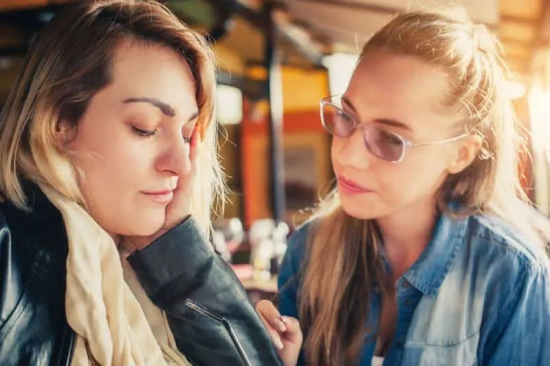 A young woman comforts a sad friend in a restaurant