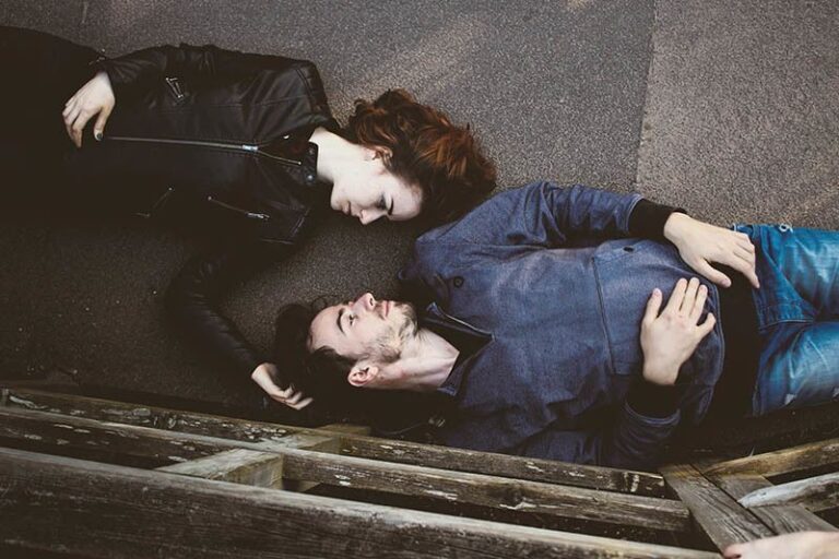 couple lying on concrete surface and looking each other