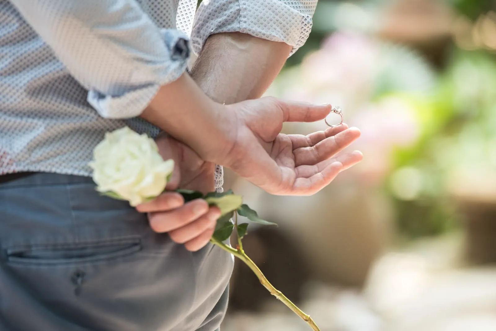 Men hide the ring and white rose behind with surprise
