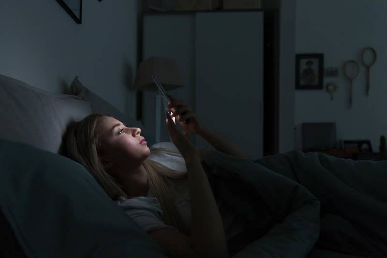 the woman lies in bed and keys on the phone