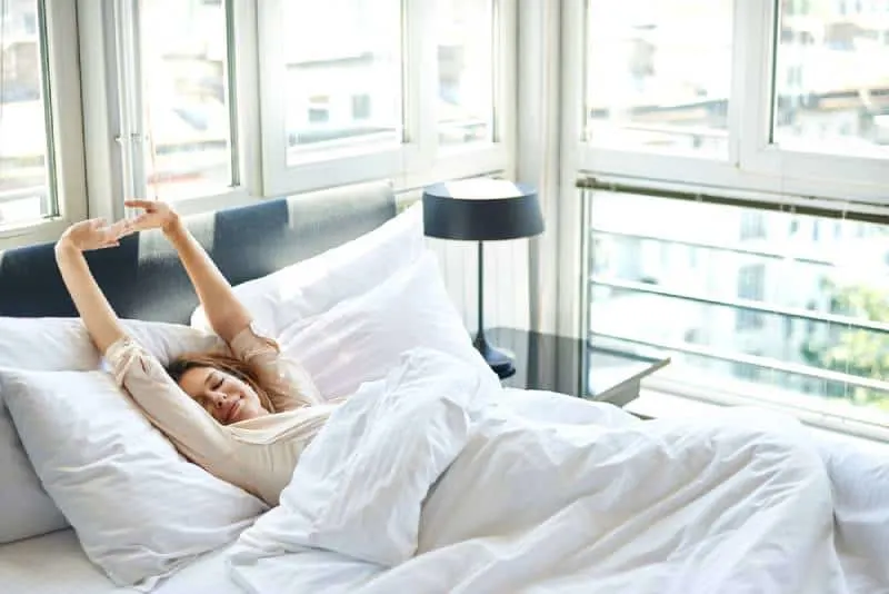 Woman stretching in bed with arms raised