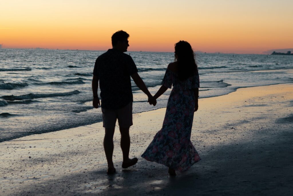 um casal de mãos dadas a passear na praia