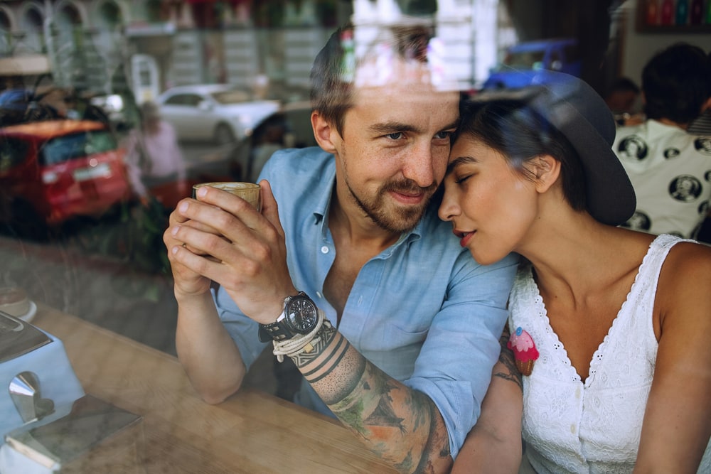 a loving couple cuddles in a cafe