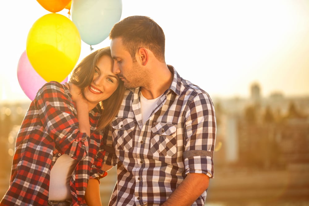 una pareja de enamorados abrazándose al aire libre junto a un globo