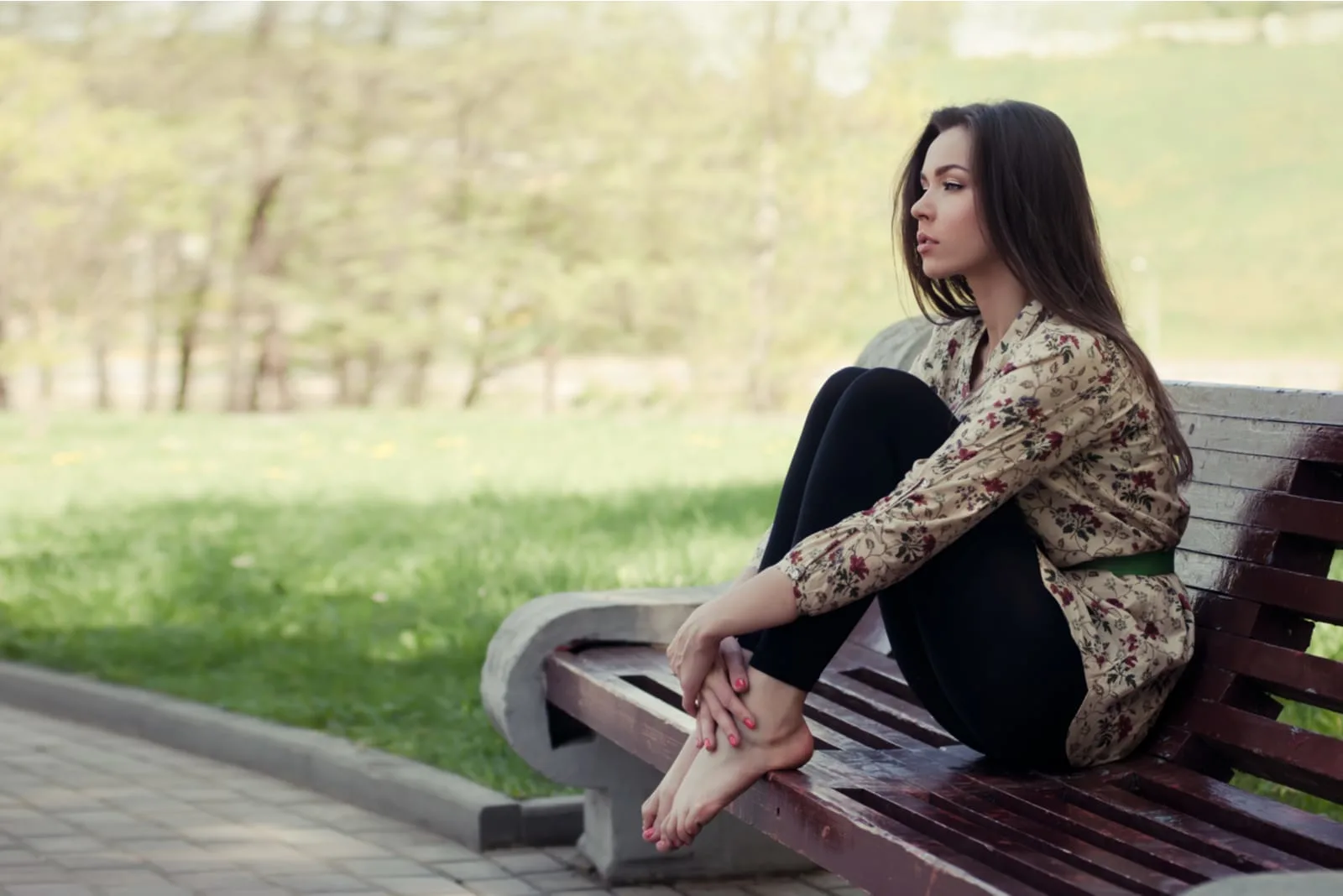 a woman with long black hair is sitting on a bench