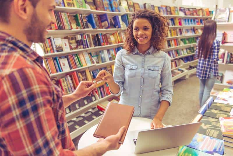 chica afro sonriendo mientras compra un libro