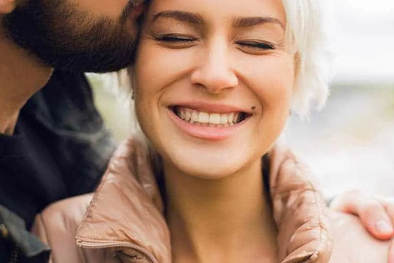 close up photo of man kisses smiling woman