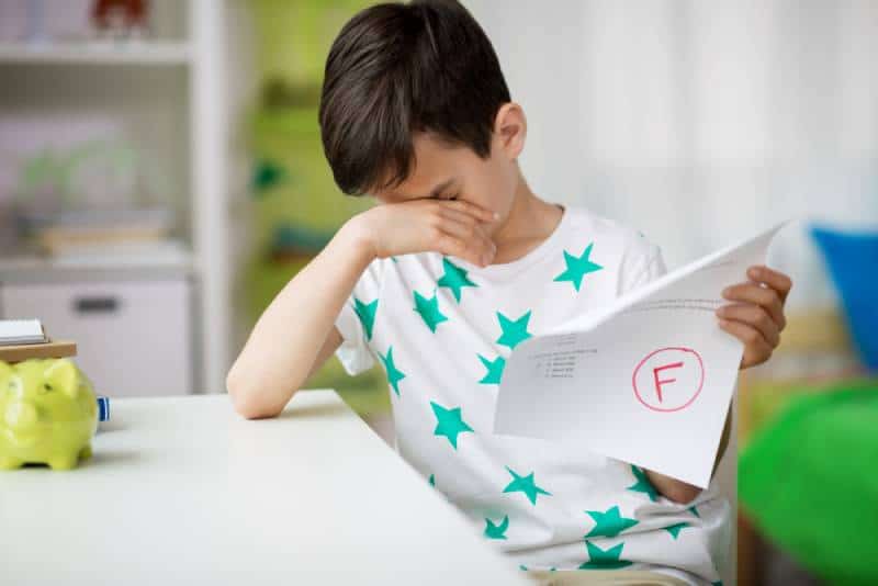crying boy holding school text with f grade