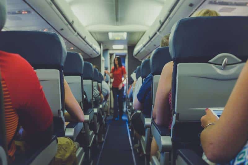 flight attendant standing between passenger seat