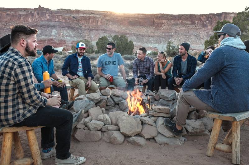 gruppo di amici seduti intorno al fuoco a chiacchierare