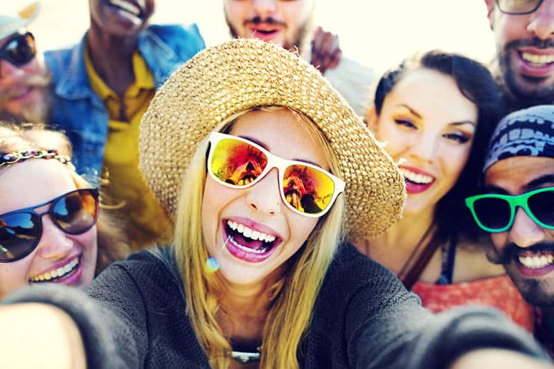 group of smiling friends taking selfie