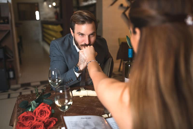 homem feliz a beijar a mão de uma mulher