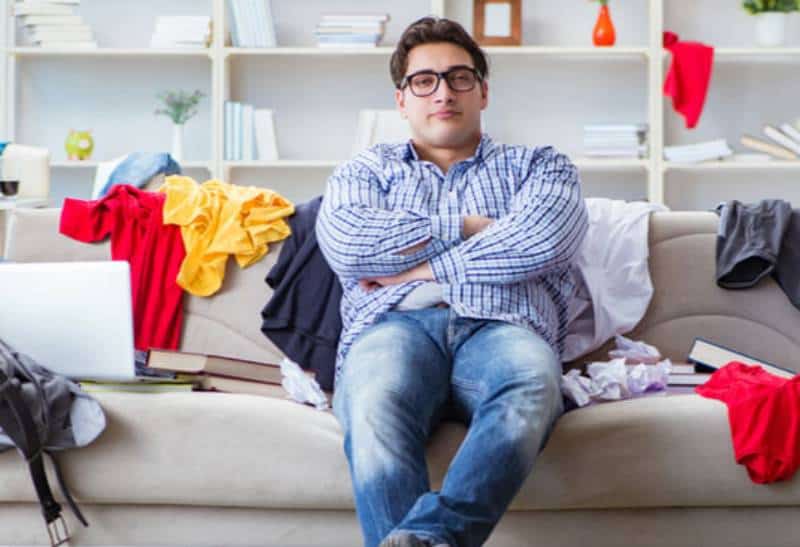 man crossed his arms in messy living room while sitting