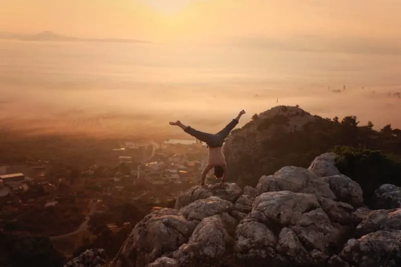 man doing handstand on boulders