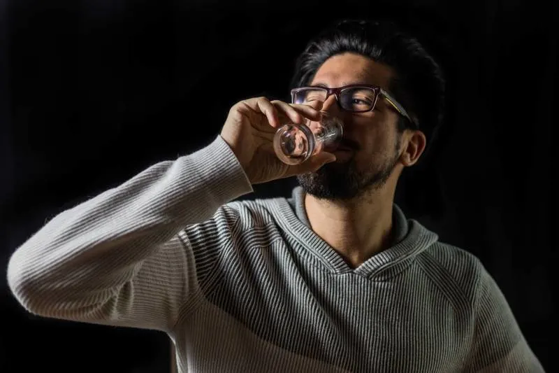 man drinking on clear drinking glass